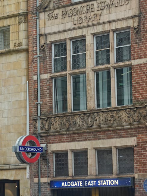 Exterior view of Edgware tube station showing the entrance and train tracks, with a pedestrian walking on the platform, area signage including a 'Way out' sign and a direction sign for buses towards Talgarth Road, and parts of the station's canopy overhead. The scene captures the typical features of a London underground station, with tiled walls, station lighting, and structural elements designed for passenger flow. This setting reflects an urban environment suitable for home relocation services provided by Removal Companies Edgware, highlighting the logistics involved in moving furniture and household items via transport connections near the station, especially during a moving day.